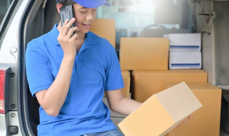 The courier sat in the car and used the phone to contact the customer.