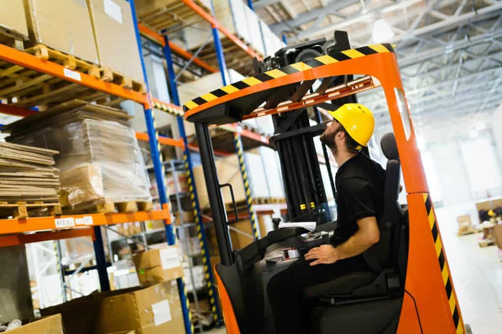 Warehouse worker doing logistics work with forklift loader